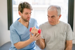 Male nurse helping older gentleman with weights